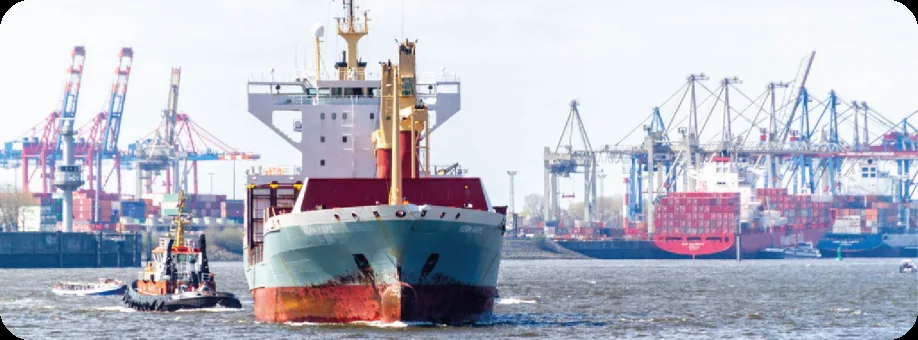 A container ship leaving a European harbor past port cranes